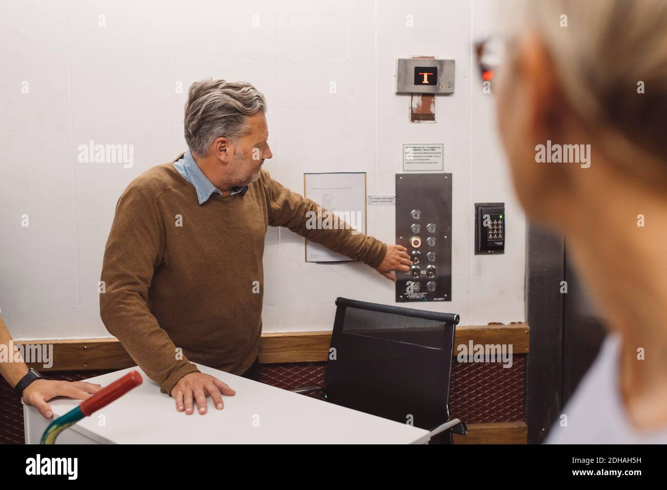 Mature businessman pressing elevator button while moving into new office Stock Photo