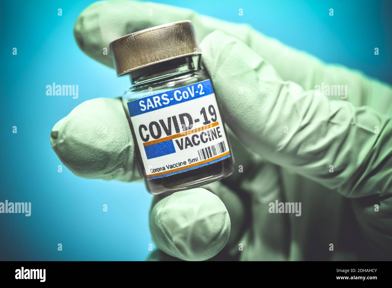 Hand im Latexhandschuh hält Injektionsfläschchen mit Corona-Impfstoff, Symbolfoto Corona-Impfmittel Stock Photo