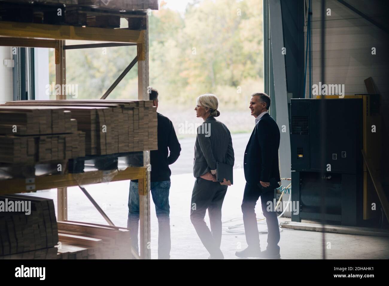 Business colleagues discussing while standing by rack at lumber ...