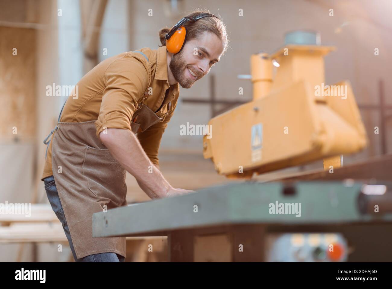 Carpentry worker sawing wooden planks with circular saw in the joinery
