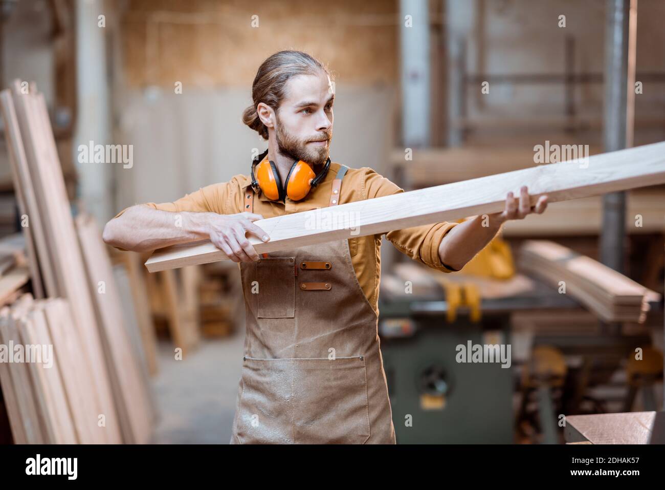 Handsome carpenter choosing planks for his woodwork at the joiners