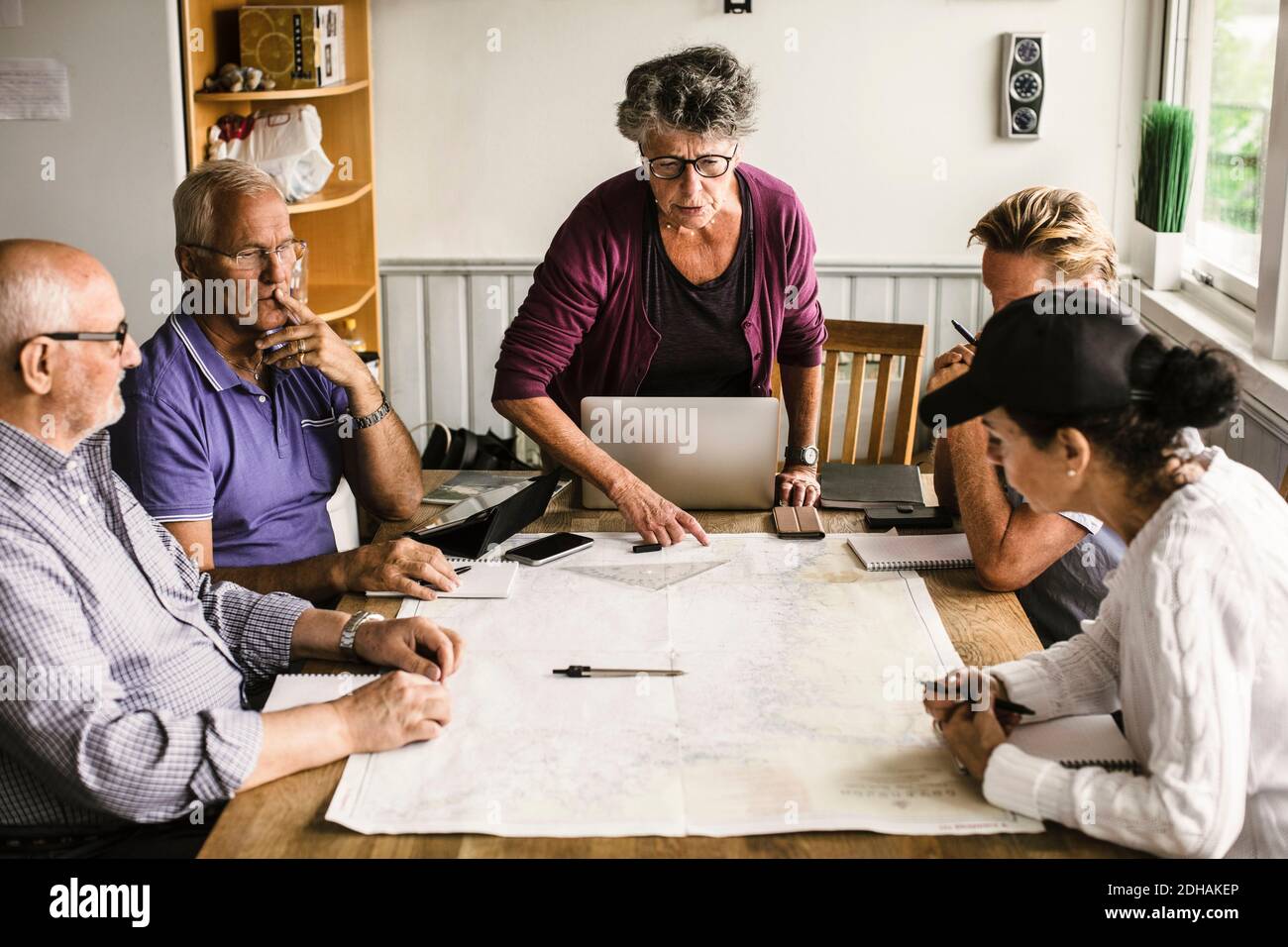 Female instructor explaining senior men and woman over map at table during navigation course Stock Photo