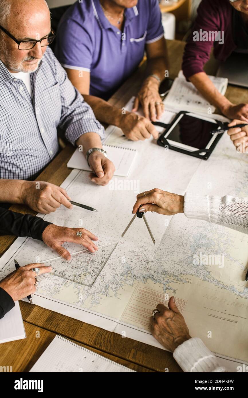 High angle view of elderly men and women with map at table during navigation course Stock Photo