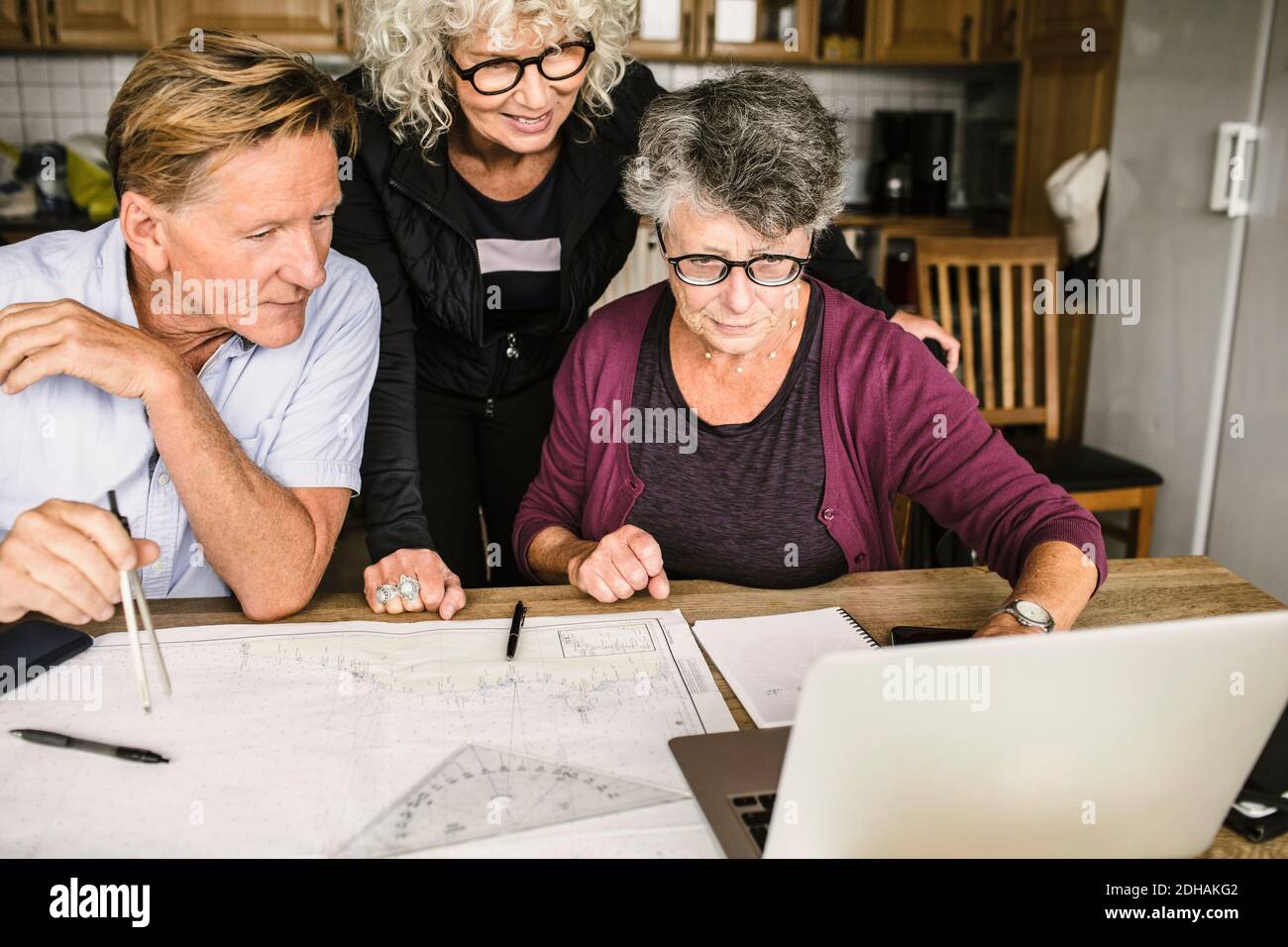 Female instructor explaining senior man and woman over laptop at table during navigation course Stock Photo