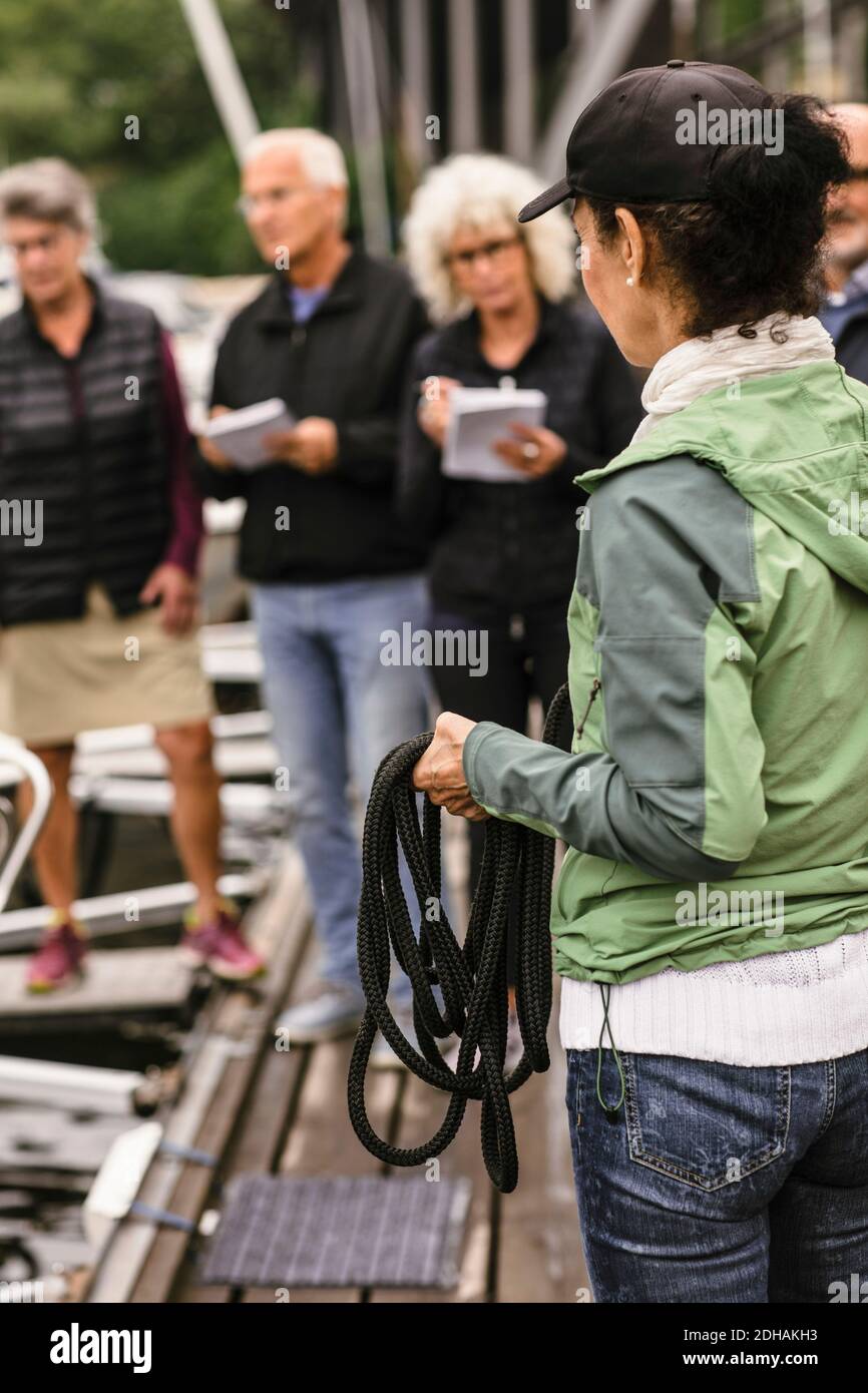 Female instructor holding rope while teaching senior men and women during boat master course Stock Photo