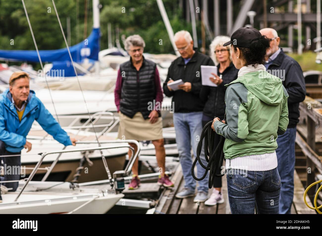 Female instructor holding rope while explaining senior men and women during boat master course Stock Photo