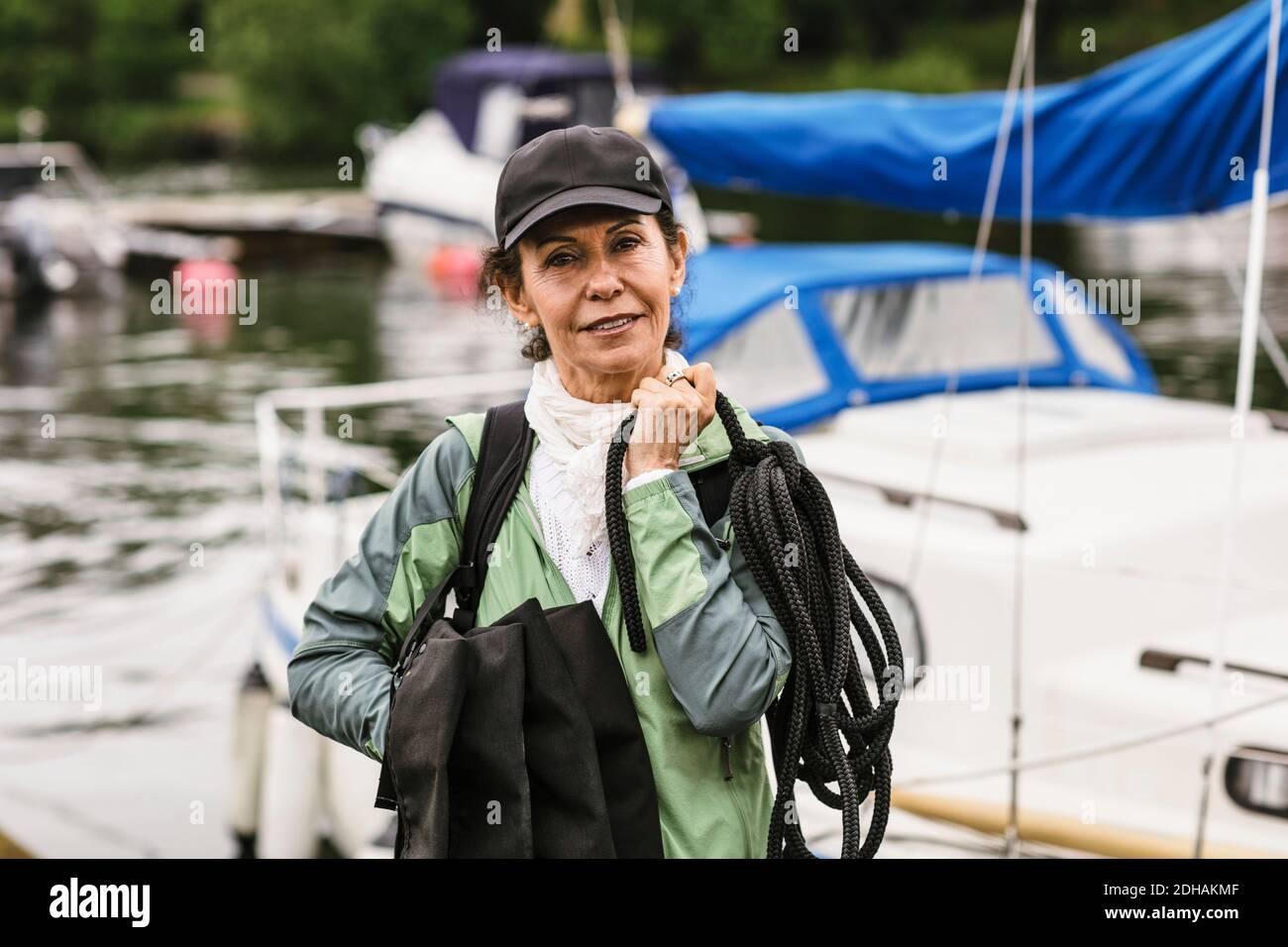 Portrait of confident female instructor holding rope and life jackets against yacht during boat master course Stock Photo