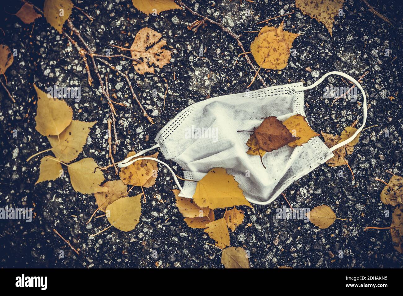 Getragene Schutzmaske liegt auf dem Boden zwischen Herbstlaub Stock Photo