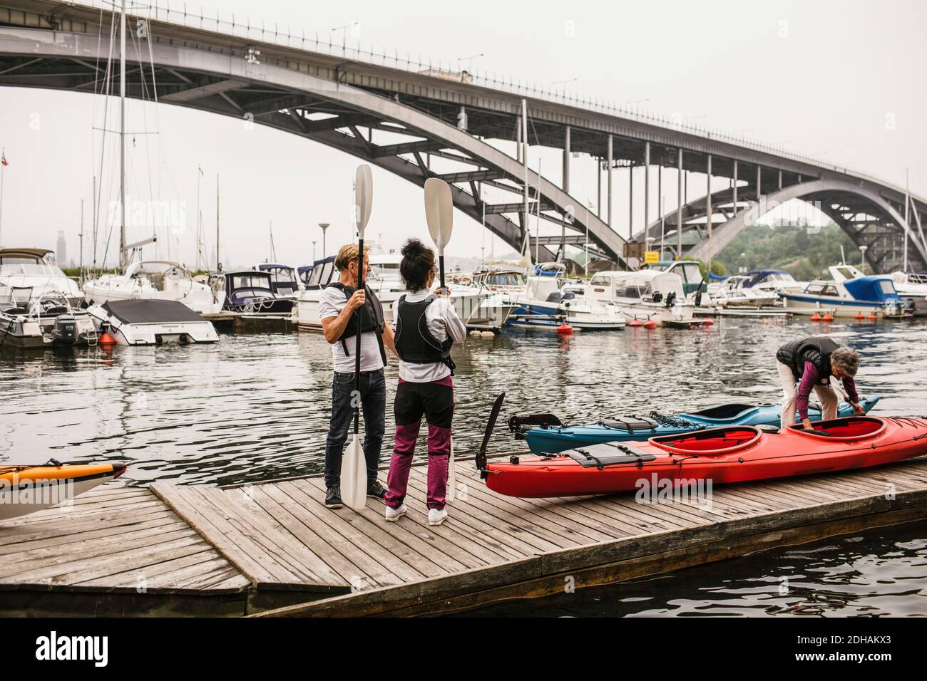 Senior male and females with kayaks and paddles on jetty during kayaking course Stock Photo