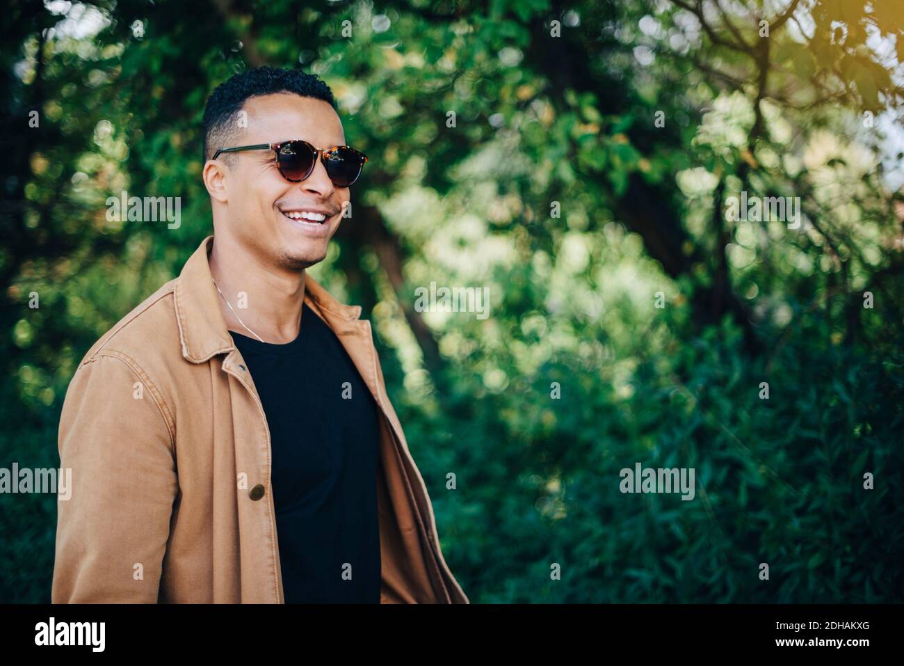 Close-up of smiling man wearing brown jacket standing by plants Stock Photo