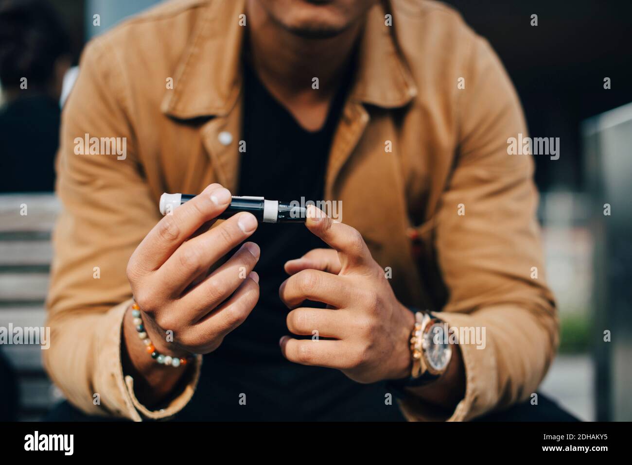 Midsection of man doing blood test while sitting on bench Stock Photo