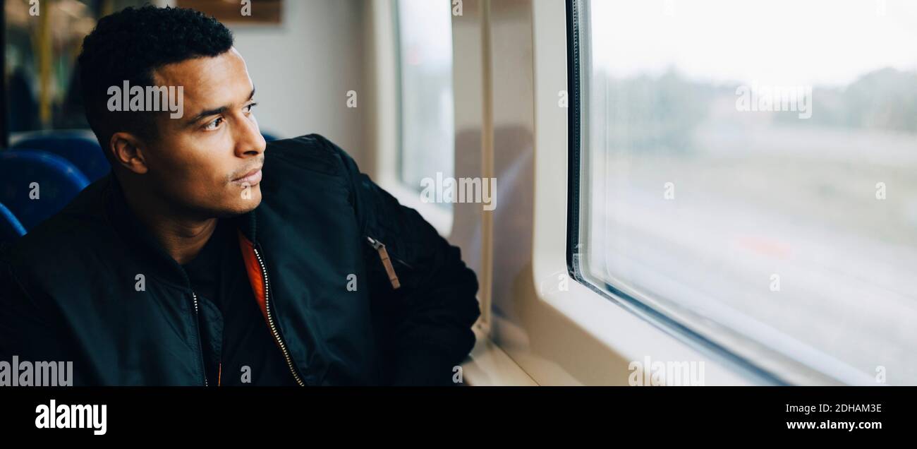 Man injecting insulin while sitting by window in train Stock Photo