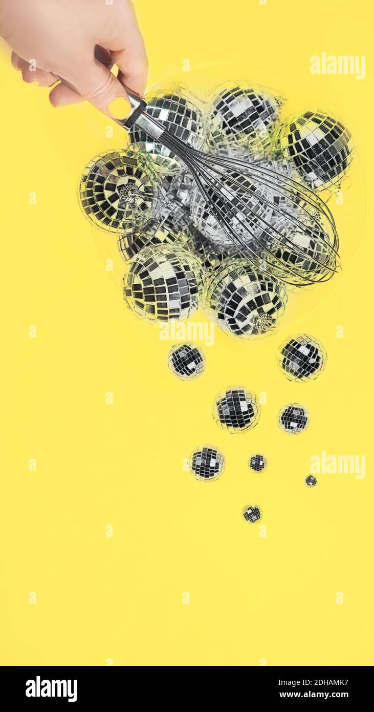 Gray silver Disco balls for decoration party shattering into small balls with whisk in hand on illuminating yellow background. Christmas New year Concept of Color of the Year 2021.  Stock Photo
