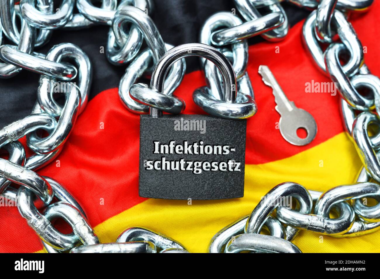 FOTOMONTAGE, Geschlossenes Vorhängeschloss mit Aufschrift Infektionsschutzgesetz auf Deutschlandfahne Stock Photo