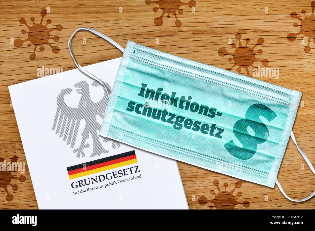 FOTOMONTAGE, Schutzmaske mit der Aufschrift Infektionsschutzgesetz, deutsches Grundgesetz und Corona-Symbolen Stock Photo