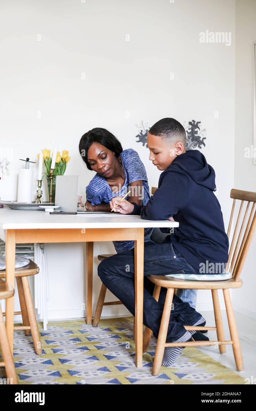 Mother helping son doing homework at dining table Stock Photo - Alamy