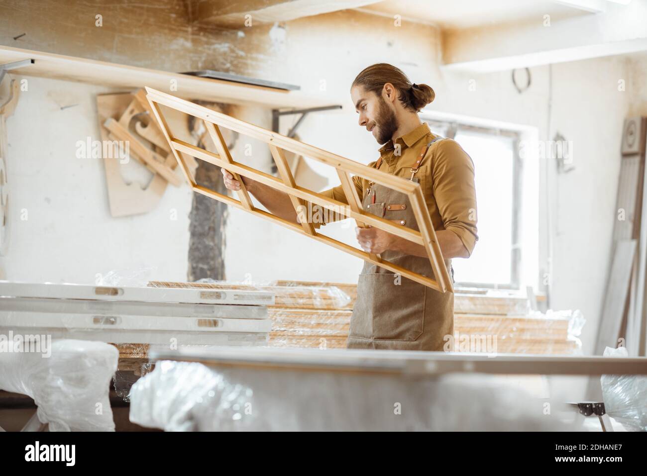 Handsome carpenter checking the quality of the window frame before the paint at the carpentry workshop Stock Photo