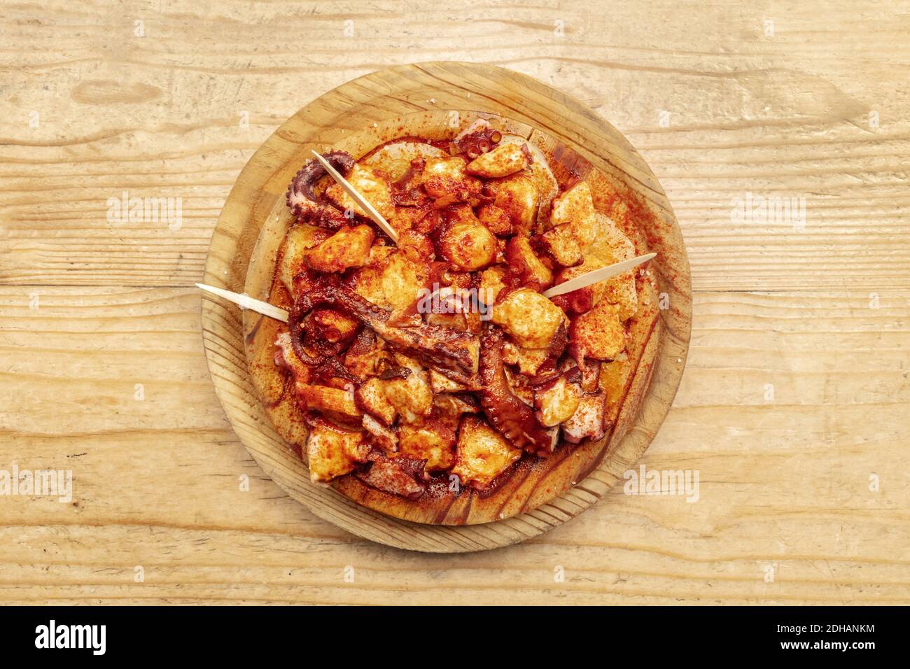 Pulpo a la gallega, an octopus with boiled potatoes and paprika, typical Spanish Galician dish, on a traditional wooden plate, s Stock Photo