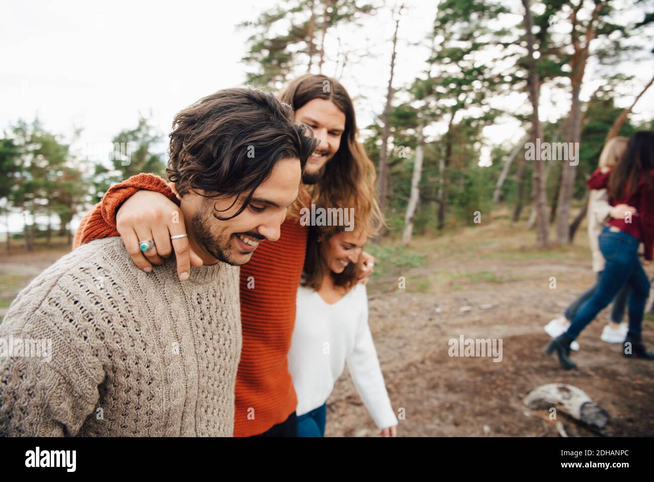 Cheerful man walking with friends in forest Stock Photo