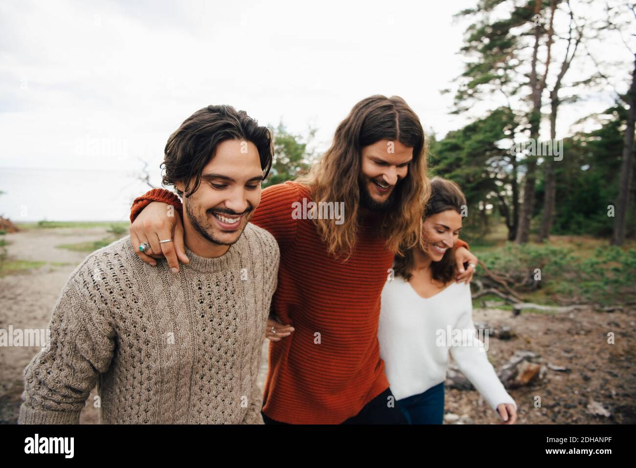 Smiling friends walking with arms around outdoors Stock Photo