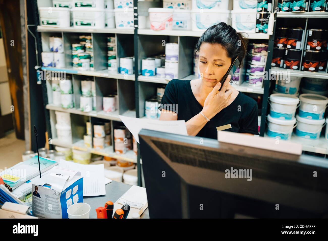 Female employee using phone while working in hardware store Stock Photo ...