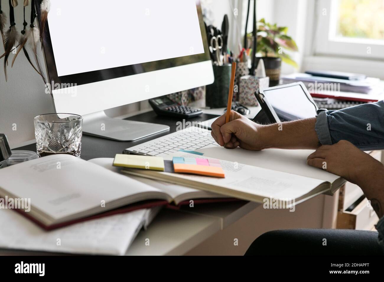 Cropped hands of businesswoman drawing on book at home Stock Photo