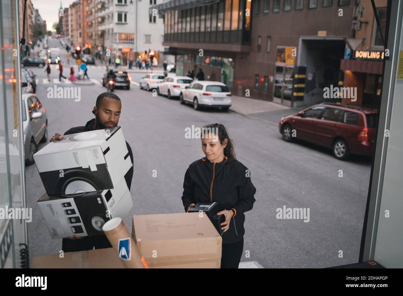 Male and female workers are stacking cardboard boxes in delivery van Stock Photo