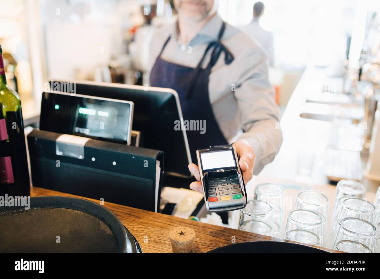 Midsection of man holding credit card reader in restaurant Stock Photo