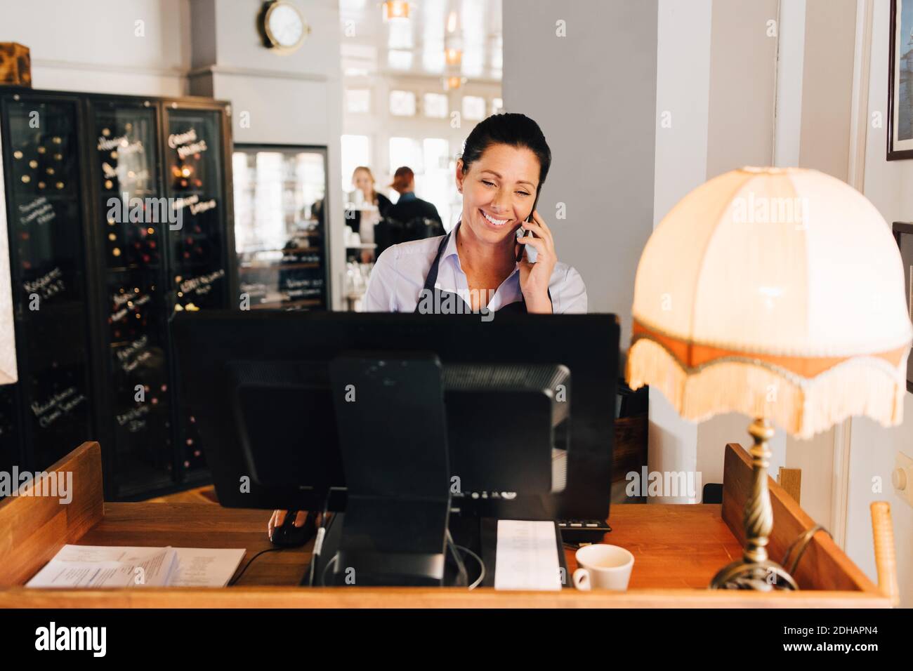 Smiling woman taking order on mobile phone in restaurant Stock Photo