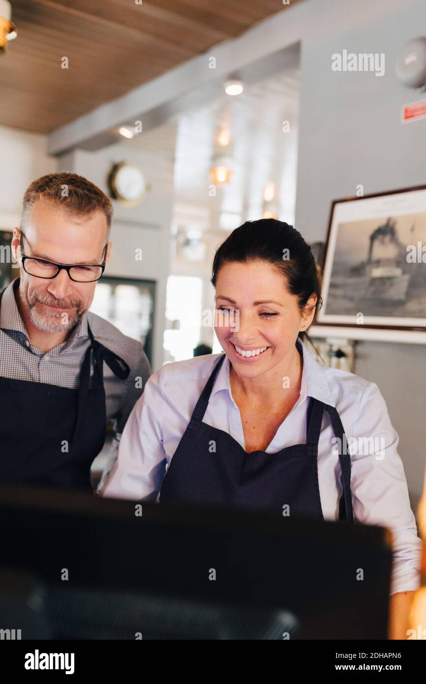 Smiling owners using computer in restaurant Stock Photo