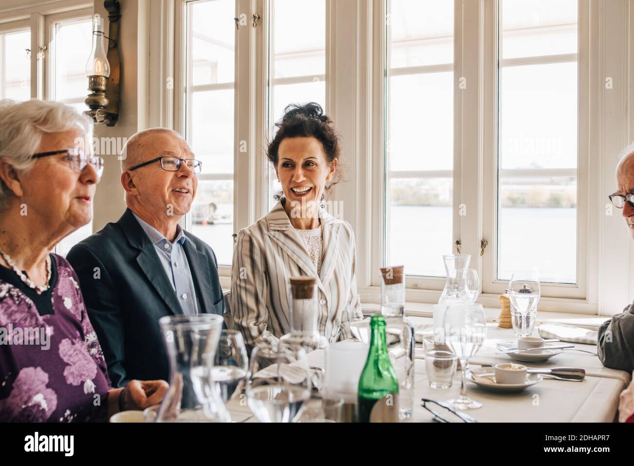 Senior friends smiling while sitting in restaurant Stock Photo