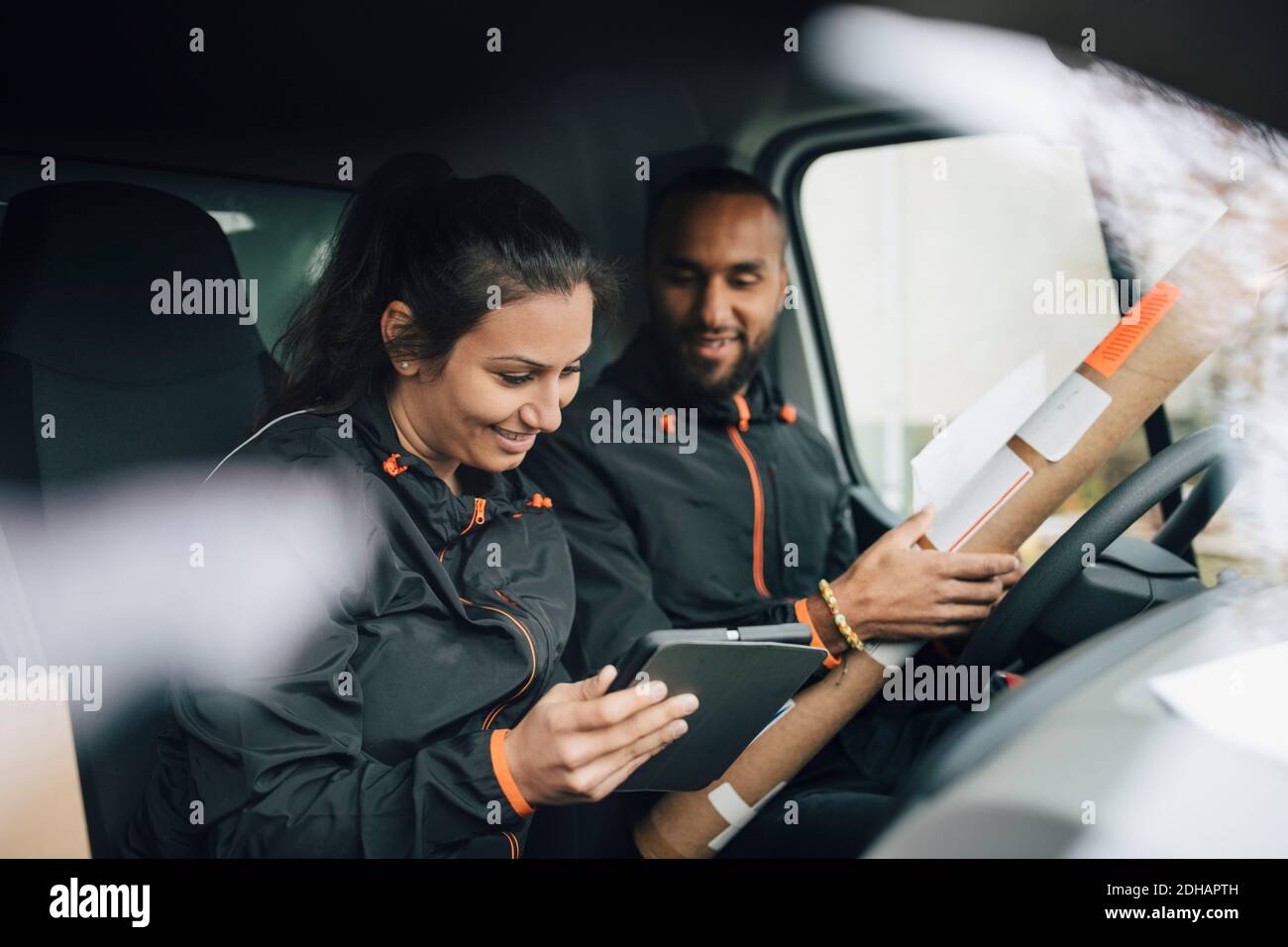 Smiling workers looking at digital tablet while sitting in delivery van Stock Photo