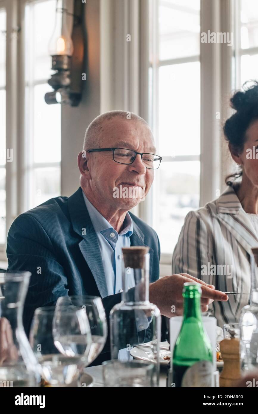 Smiling senior man sitting by table in restaurant Stock Photo