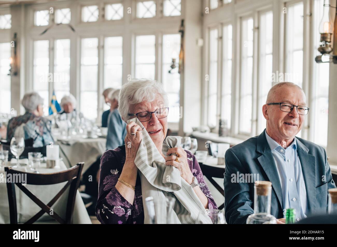 Senior woman crying while male friend smiling in restaurant Stock Photo