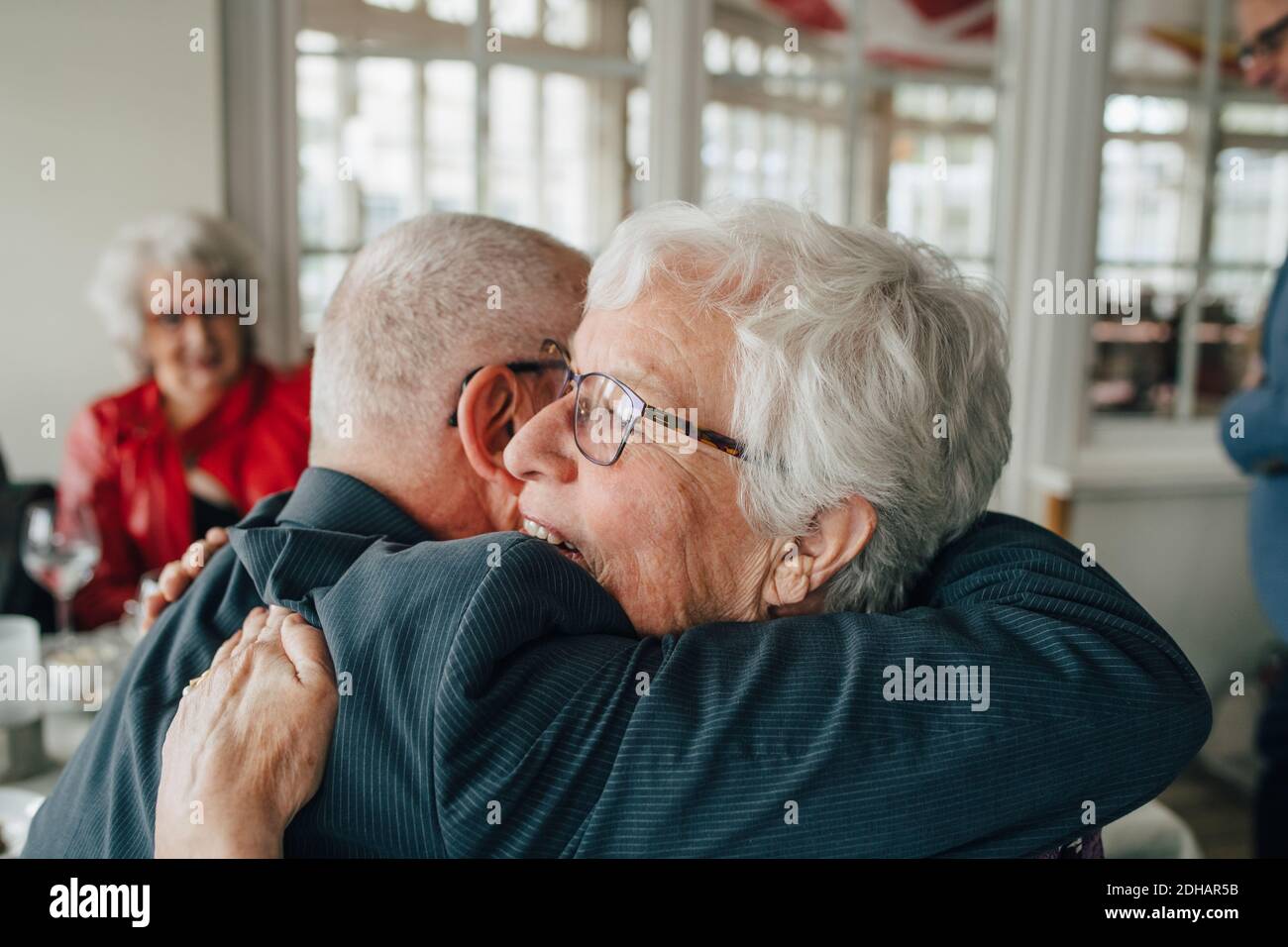 Senior man embracing woman while sitting in restaurant Stock Photo