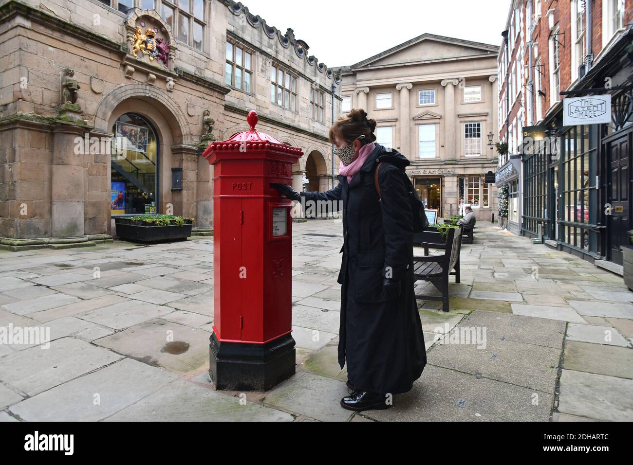 Woman posts a letter in a Victorian hexagonal shaped post box in Shrewsbury, Uk.  One of only 50 made they were designed by I.W. Penfold and made by C Stock Photo