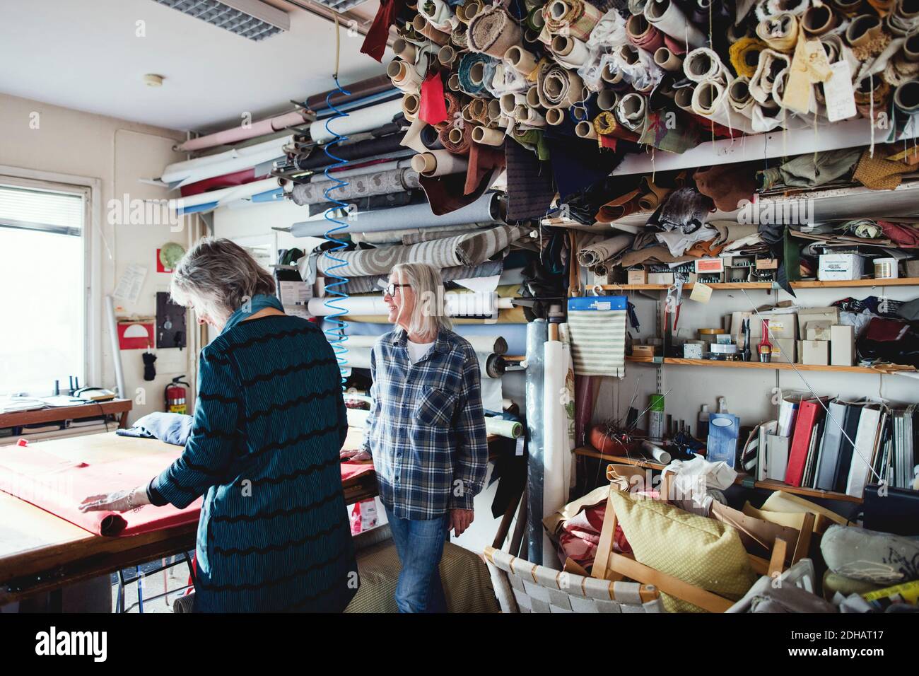 Colleagues working together while standing by shelves at workshop Stock Photo