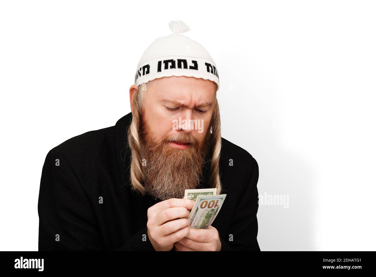 Greedy bearded jewish man counting his money. Thrifty jew with sidelocks in white yarmulke isolated on white background Stock Photo