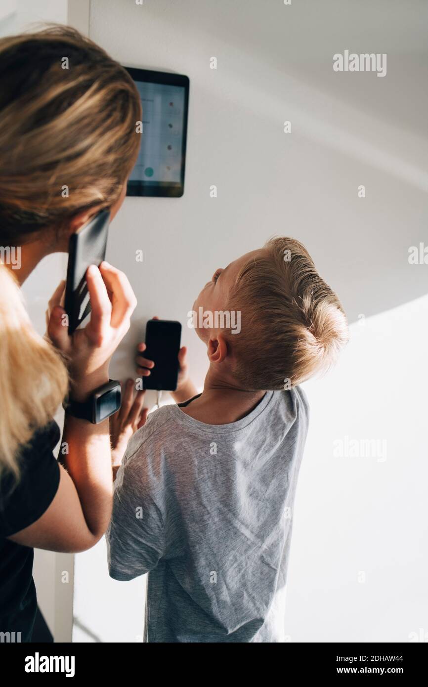 Siblings using digital tablet mounted on wall at home Stock Photo