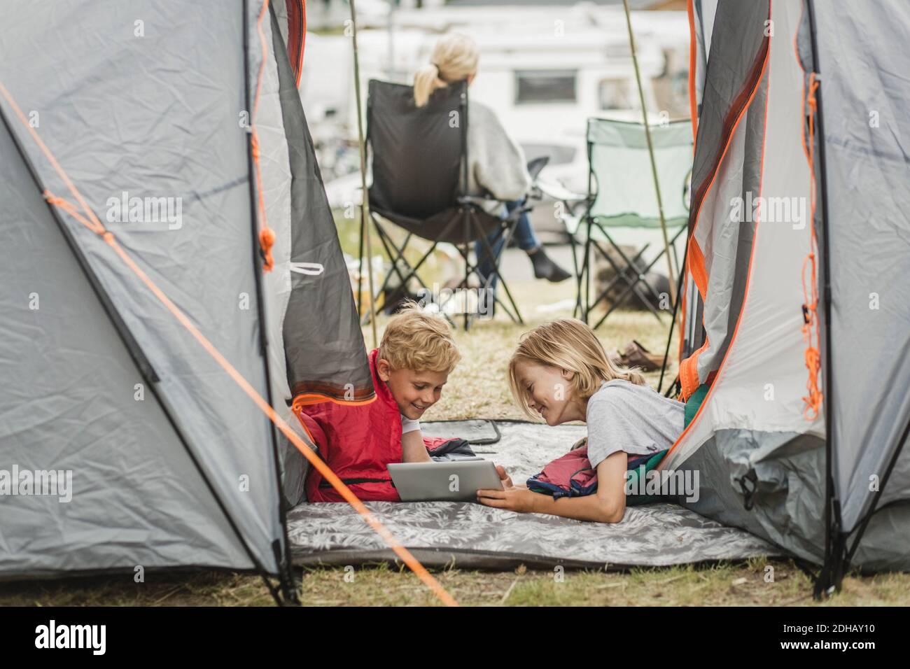 Sisters spending time in a tent on camping. Children using tablet playing games  online during summer vacation - a Royalty Free Stock Photo from Photocase