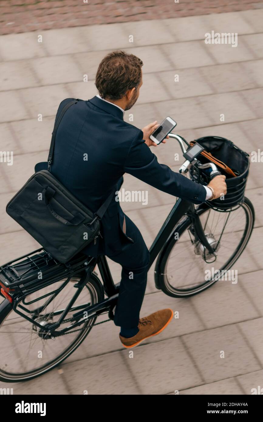 High angle view of businessman riding bicycle on footpath in city Stock Photo