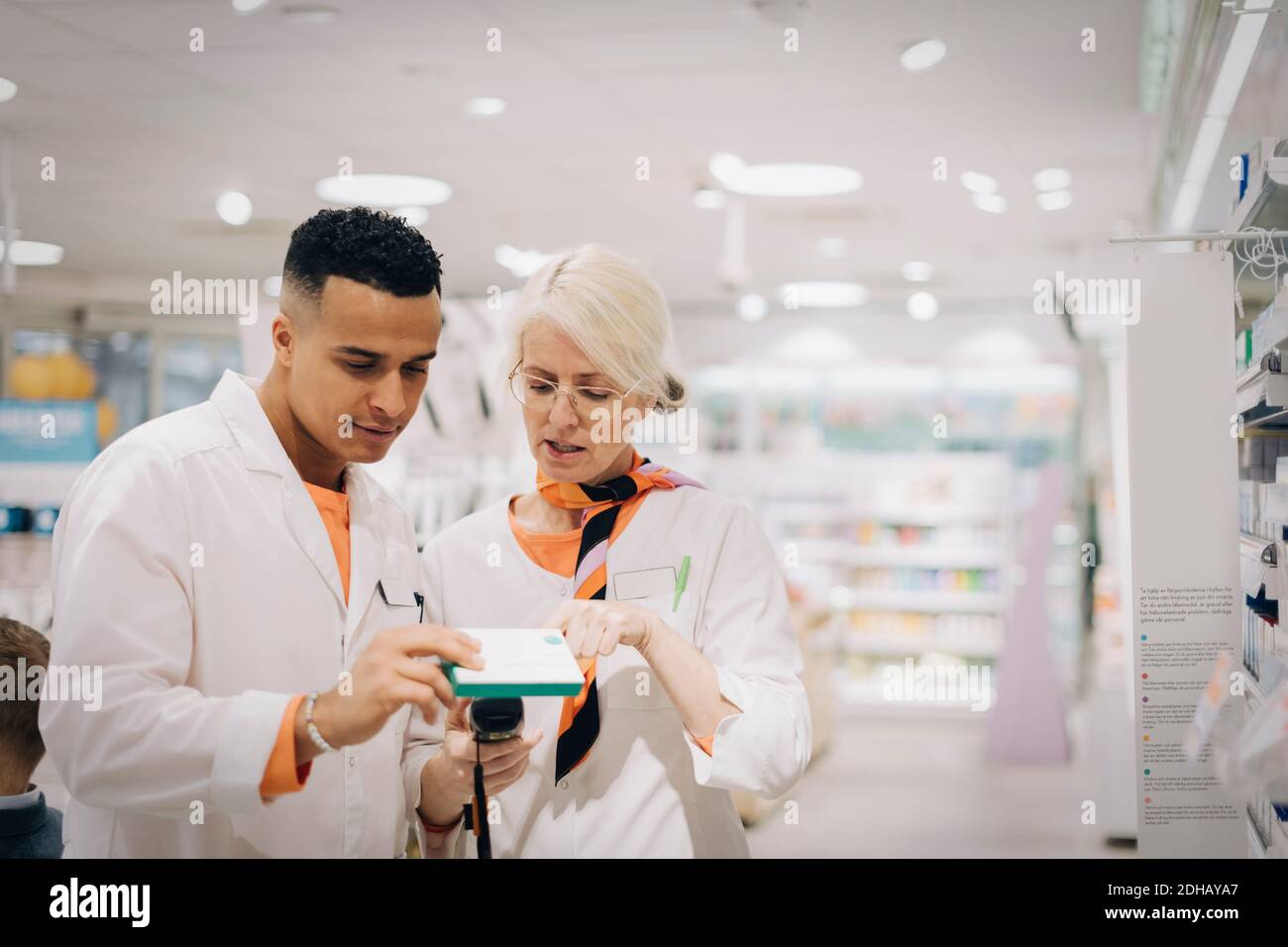 Colleagues checking medicine with bar code reader at pharmacy store Stock Photo