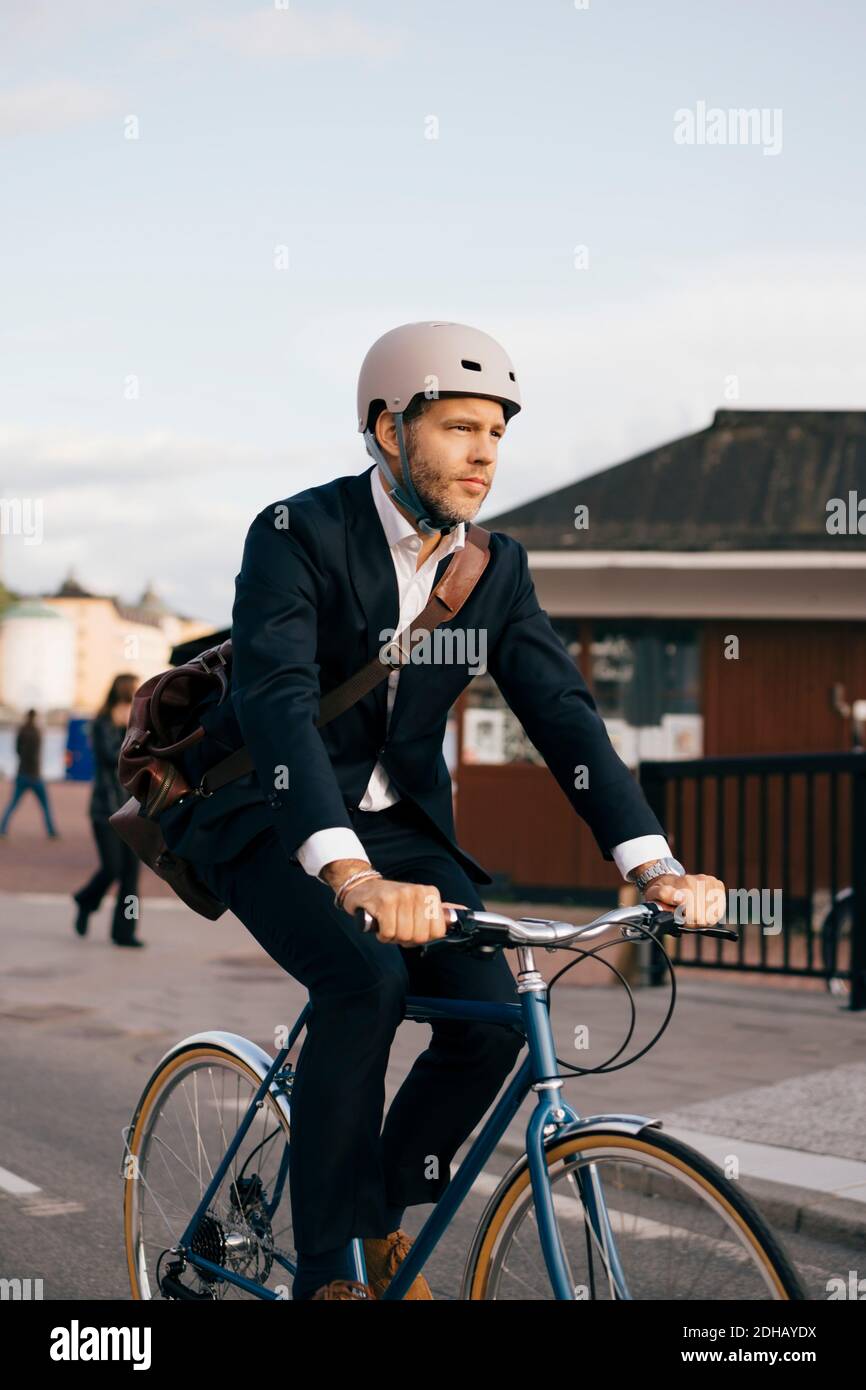 Confident businessman riding bicycle on street in city Stock Photo