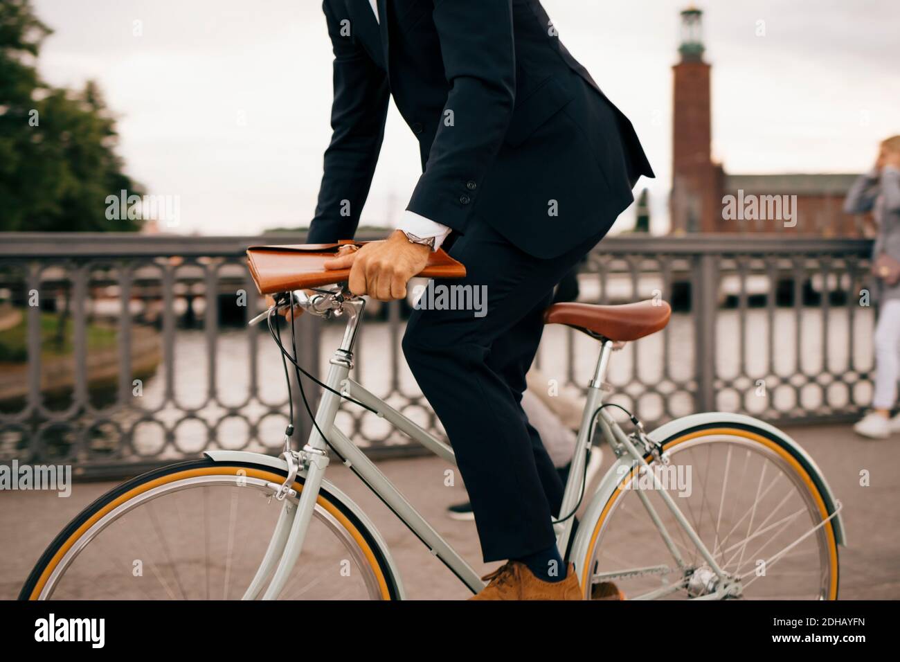 Low section of businessman riding bicycle on bridge in city Stock Photo