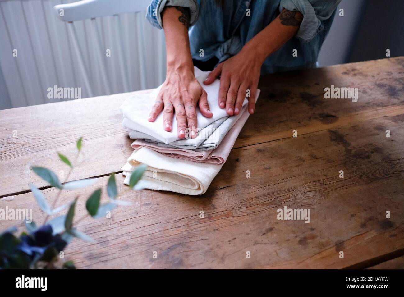 Midsection of woman folding napkins while standing at wooden table in kitchen Stock Photo