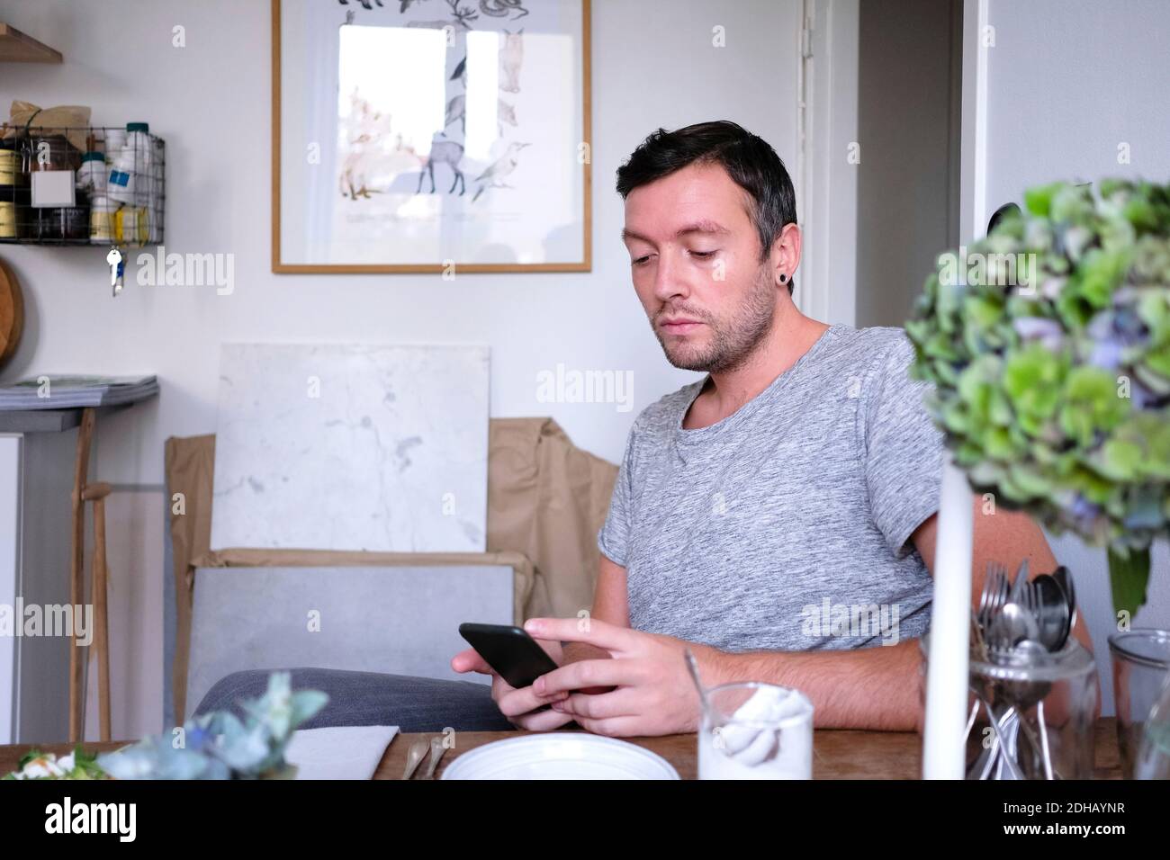 Man using mobile phone while sitting by table at home Stock Photo