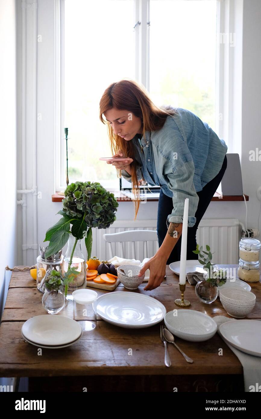 Woman photographing plates and food on table at home Stock Photo