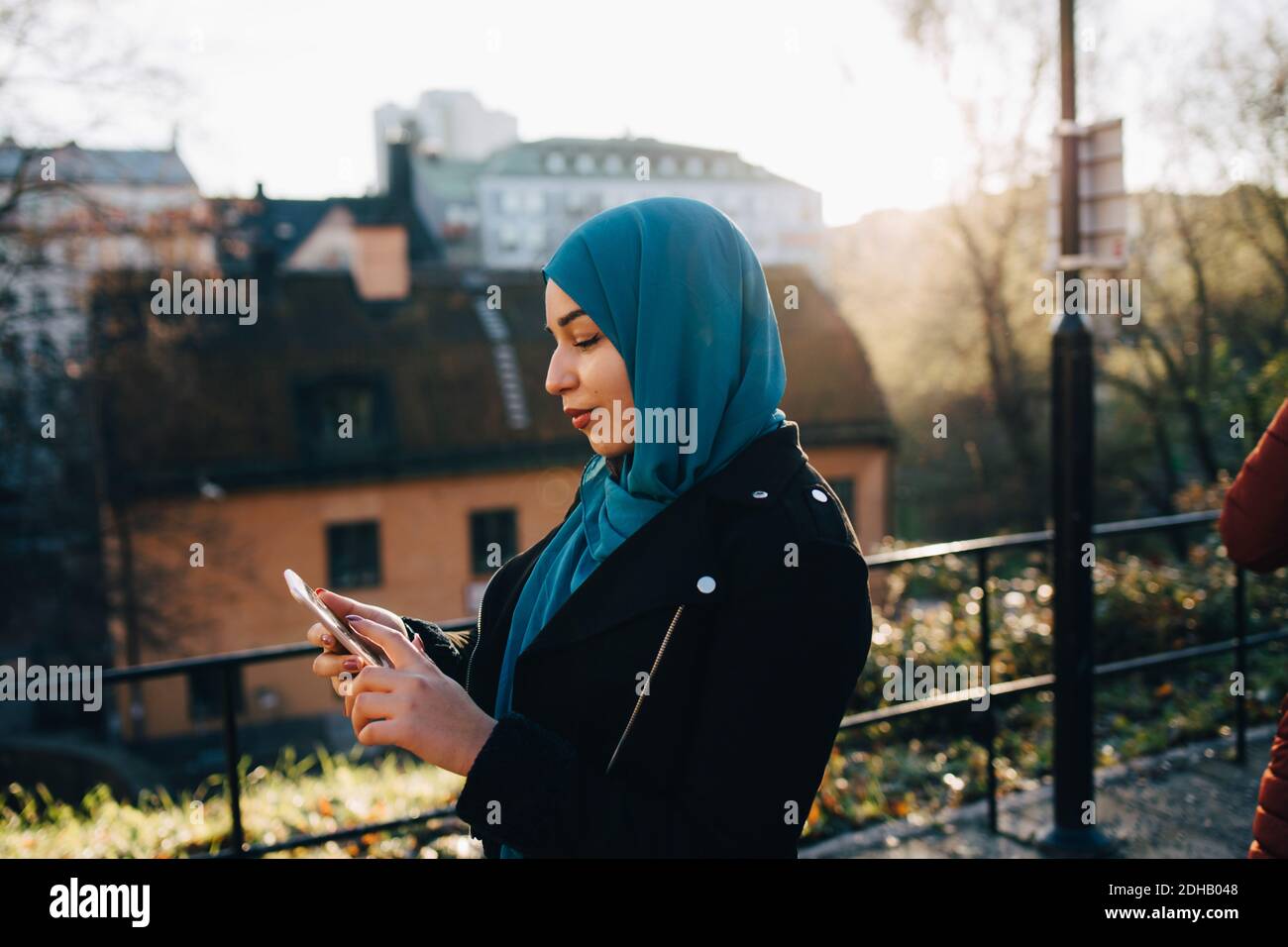 Young Muslim woman wearing hijab using smart phone in city Stock Photo ...