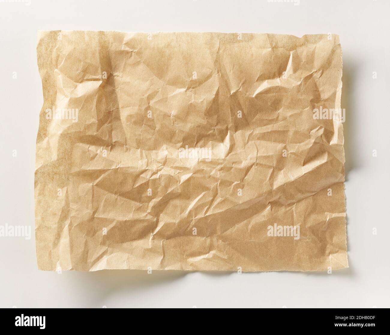 crumpled brown baking paper sheet on white table, top view Stock Photo