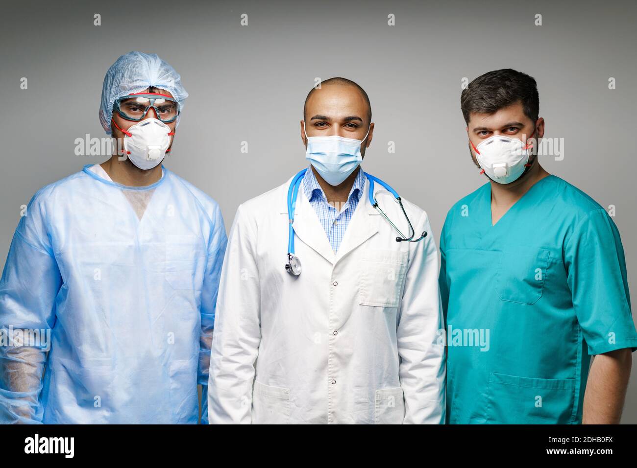 Doctors In Uniform Male doctors in medical uniform wearing masks standing against grey ...